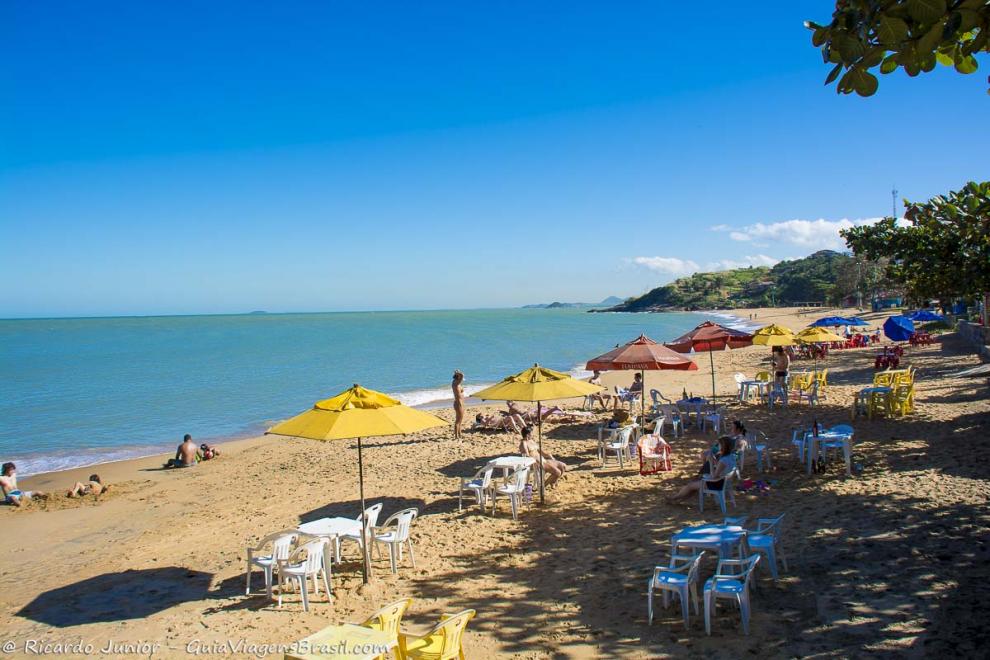 Imagem de familias brincando com seus filhos na areia e guarda sol na Praia dos Coqueiros.